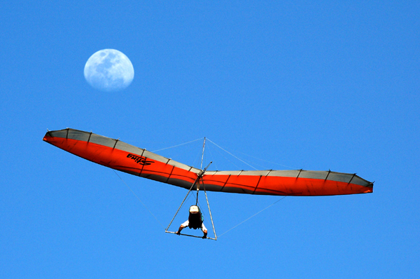 Hanglider cruising with moon backdrop